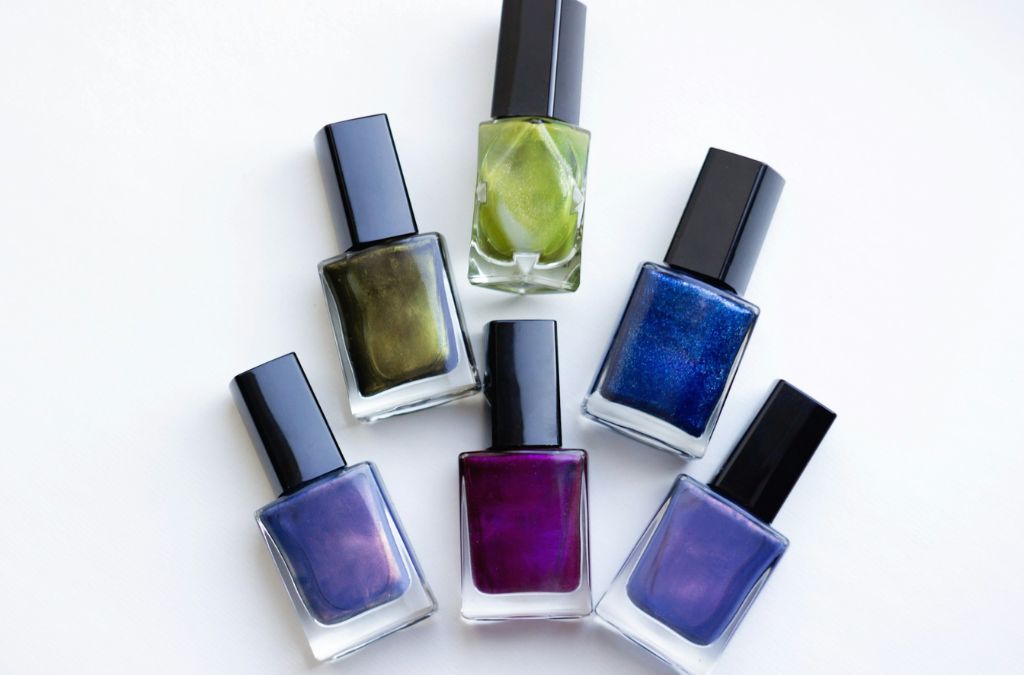 Best Nail Colors displayed in nail polish bottles featuring blue, green, purple, and other shades.
