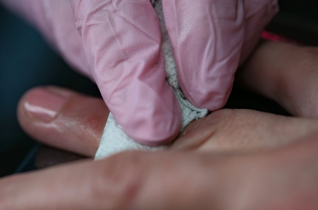 How to Remove Gel Nail Polish at Home Without Damaging Your Natural Nails 4 Close-up of hands during a nail treatment showing how to remove gel nail polish carefully.