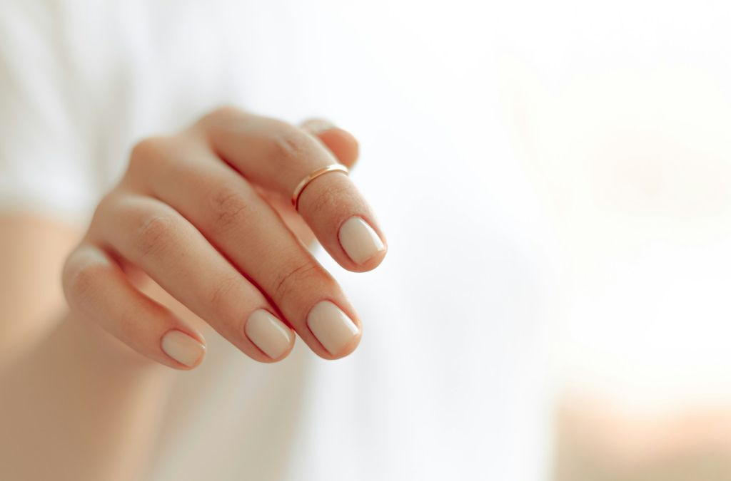 How to Make Your Nails Grow Stronger with healthy nail care habits, showing a close-up of neatly shaped nude manicured nails.