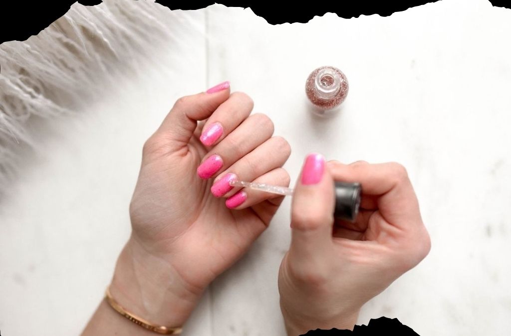 Nail polish on gel nails with bright pink polish being applied to fingernails.