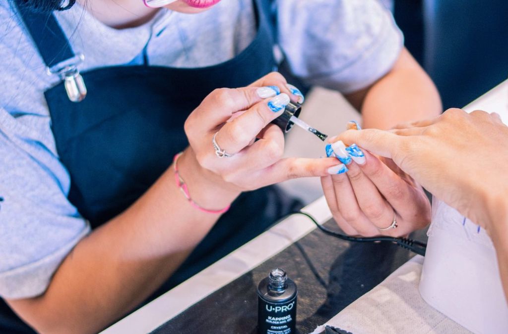 Nail tips nails featuring colorful blue nail art designs during a manicure.