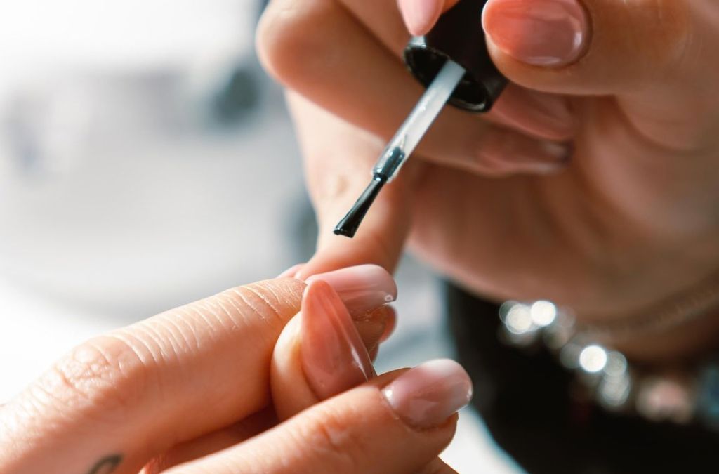Nail polish on gel nails being carefully applied with a small nail polish brush.